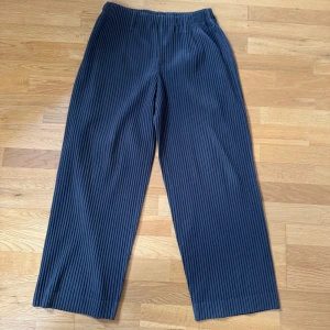Svarta plisserade byxor från Homme Plissé Issey Miyake - Snygga svarta plisserade byxor från Homme Plissé Issey Miyake. Tillverkade i 100% polyester med en bekväm och stilren design. Perfekta för en modern och avslappnad look. Storlek 2=M. Använda under 5 gånger
