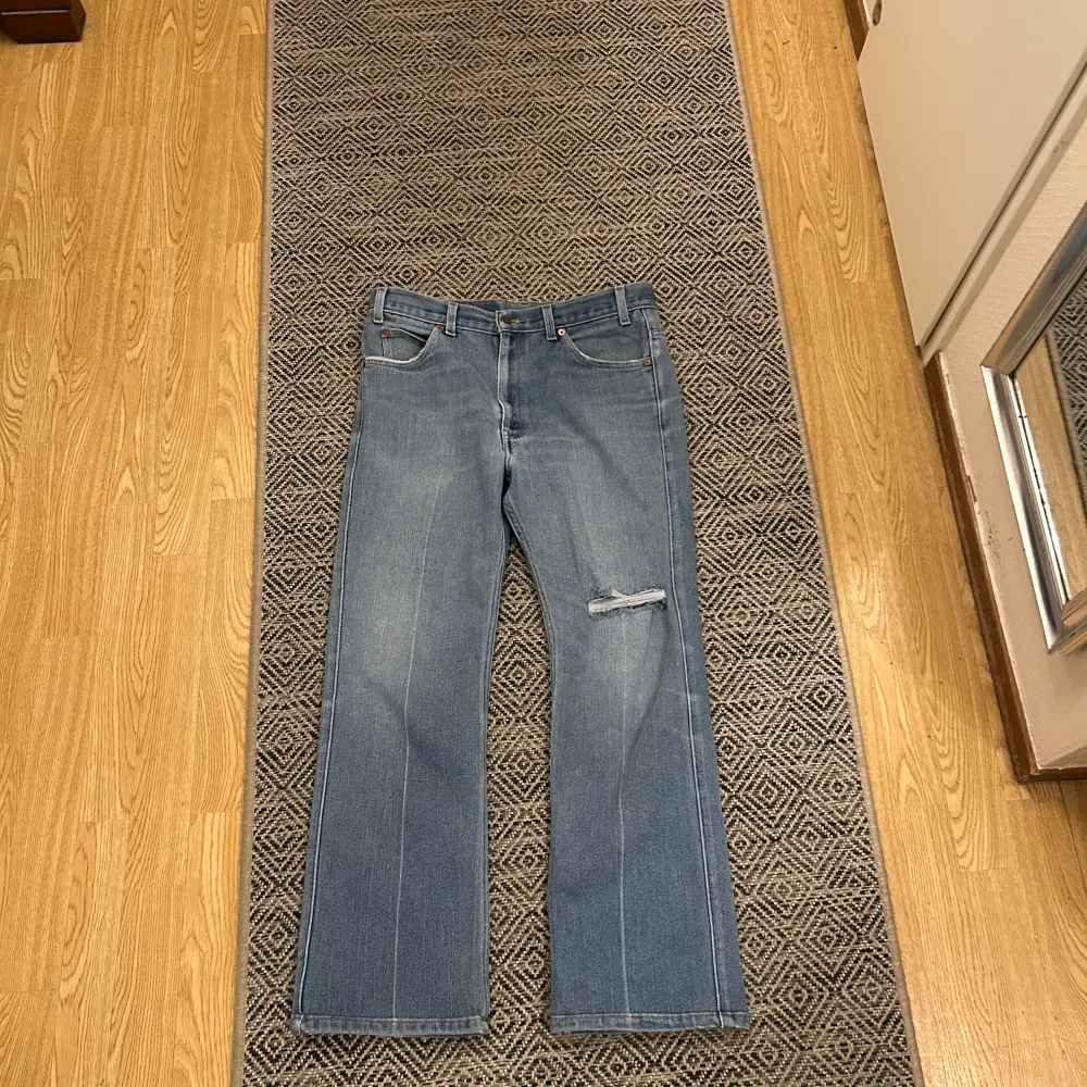 Säljer ett par klassiska Levi's 517 jeans i blå denim. De har en bootcut-stil och en snygg slitning på ena benet. Perfekta för en avslappnad look. Igentliga storleken är 34/30. Farkut & Housut.