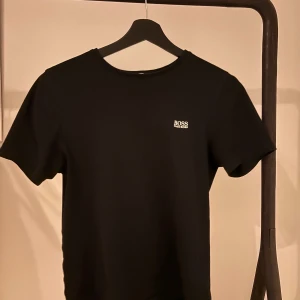Svart t-shirt från Boss - Snygg svart t-shirt från Boss med liten logga på bröstet. Perfekt för en stilren look. Tillverkad i mjukt material för extra komfort.
