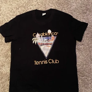  Casablanca T-shirt  - Snygg svart t-shirt från DERNM med ett coolt Casablanca Tennis Club-tryck på framsidan. Perfekt för en avslappnad stil med en touch av sportig elegans.           Saknar tag 