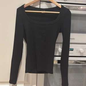 Svart långärmad topp från Gina Tricot - Säljer en stilren svart långärmad topp från Gina Tricot. Toppen har en enkel design med en rundad halsringning och är tillverkad i ett mjukt ribbat material som ger en bekväm passform. Perfekt för att matcha med olika outfits.