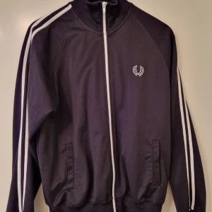 Fred Perry tracktop - Svart Fred Perry tracktop. Tillverkad i Portugal. Rekommenderas!