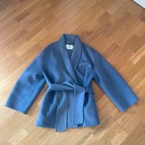 Kort kappa Stylein - Kort blå kappa från Stylein. Bilderna ger inte rättvisa ljus då solen låg på. Men bild 3 skulle jag säga stämmer överens med färgen. Knappt använd, så är som ny!  Väldigt bekväm och snygg. 