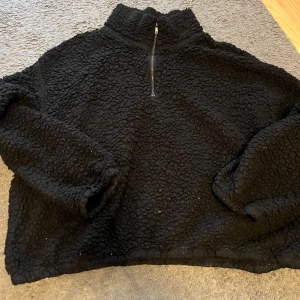 Svart fleece tröja från H&M - Mysig svart fleece tröja från H&M i storlek L. Perfekt för kalla dagar med sin fluffiga och varma design. Tröjan har en halv dragkedja framtill och är långärmad. Den är i bra skick. 
