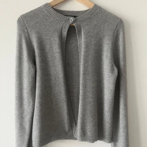 Trendig kofta från Gina Tricot  - Superfin grå trendig tunnstickad kofta med en knapp från gina tricot. Knappt använt. Den har inga skador. Helt slutsåld.