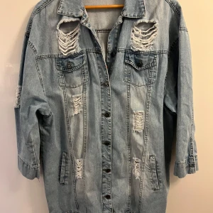 Sliten jeansjacka från Just B - Säljer en cool och sliten jeansjacka från Just B i storlek XL. Jackan har en ljusblå tvätt med flera slitna detaljer som ger den en edgy look. Den har långa ärmar och knappar framtill. Kvalite 8/10. Nypris 699kr. Mitt pris 99kr. För kvinna.