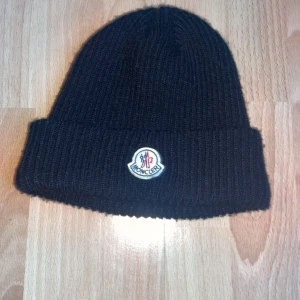 Moncler mössa  - Moncler mössa i bra skick, perfekt för hösten och vintern. Bra design och varm, idealisk för kalla dagar.