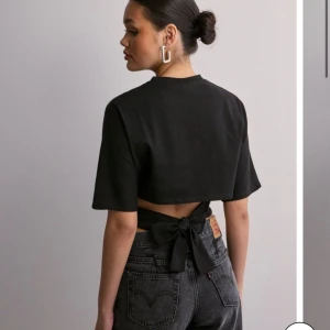 Svart T-shirt rosett nelly - Interessekoll på den populära toppen med rosett i ryggen från Nelly, använd 2 gång 🥰 OBS! Laddat upp massa nytt fint till hösten så gå in på min profil och kolla så kan jag samposta 🥰🌸