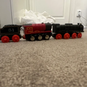 Svart och röd leksakståg med  hjul - Säljer ett coolt leksakståg i svart och rött med  hjul. Tåget har detaljer som '51' och 'HIRO'S TENDER' på sidorna. Perfekt för barn som älskar tåg och vill ha något unikt att leka med. Tåget är i bra skick och redo för nya äventyr på rälsen!