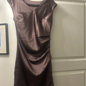 Lila klänning från Saint Tropez - Snygg lila klänning från Saint Tropez i storlek S. Den har en elegant och stilren design med korta ärmar och en smickrande passform. Perfekt för höst och vinter till både vardag och fest. Materialet ser ut att vara av syntet, vilket ger en fin glans.