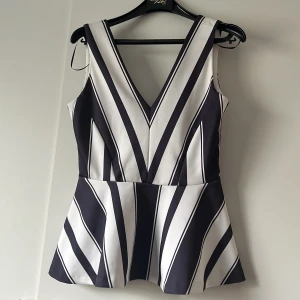 Svartvit randig topp/ blus från H&M - Säljer en superfin svartvit randig stilig blus eller Topp från H&M i storlek S. Den har en v-ringad design och dragkedja i ryggen. Perfekt för både vardag och fest! 🖤🤍