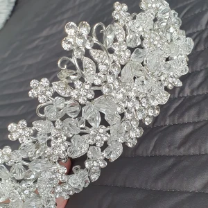 Glittrig diadem med pärlor - Säljer ett fantastiskt glittrigt diadem med vackra pärlor och detaljer. Perfekt för fest eller speciella tillfällen. Diademet har en elegant design med blommönster och är i en skimrande silverfärg. Det är både stilrent och iögonfallande, vilket gör det till ett måste för att komplettera din look.