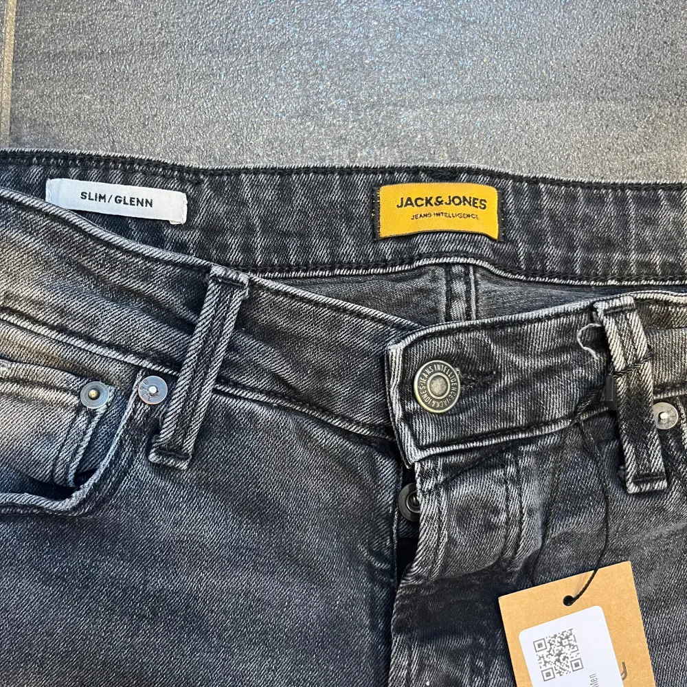 Säljer ett par snygga gråa jeans från Jack & Jones i modellen Slim/Glenn. De har en slim passform  med snygga slitningar och är i nyskick. Perfekta för både vardag och fest! 🖤. Jeans & Byxor.