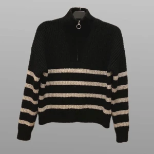 Svart och vit randig stickad tröja - Mysig stickad tröja i svart och vitt med randigt mönster. Den har en hög krage med dragkedja och långa ärmar. Perfekt för kyliga dagar när du vill vara både varm och stilren. Passar bra till både jeans och kjol!