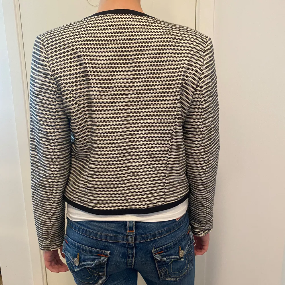 Snygg och stilren randig kavaj från Stockh lm i svart och vit. Den har långa ärmar och dekorativa knappar framtill. Perfekt för både vardag och fest. Passar bra till jeans eller kjol för en chic look. Storlek 38. Jackor.