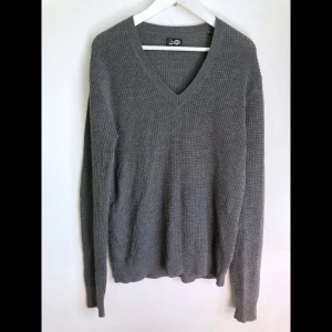 Våffelstickad mörkgrå tröja, ull, S 44/46, Cheap Monday, finstickad, V-ringad, klassisk - Finstickad V-ringad grå tröja i ullmix. Finns tecken på användning i form utav noppor, främst på ärmarna och utefter sidorna. Storlek: S, bröstvidd: 50 cm, axelbredd: 46 cm, längd fram från axeln: 66 cm, ärmlängd: 70 cm.