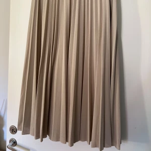 Beige plisserad kjol från H&M - Skirt reach under the knees. Size M-L