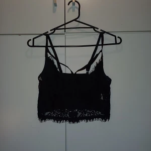 Svart spetts topp - En svart kortare spetts topp. Den passar perfekt tillsamans med en kavaj och ett par jeans eller kostymbyxor. Har anvönts mpnga gånger då jag älskar den men har växt ur den.