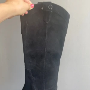 Svarta mocka cowboy boots från H&M - Säljer ett par snygga svarta cowboy boots i mocka från H&M. De har en spetsig tå och en liten klack som ger en cool look. Perfekta för höst och vinter, och funkar lika bra till vardags som till fest. Skorna är i bra skick och redo för nya äventyr!🥹Tyvär passa inte skorna mig eftersom att jag har en högre storlek så de väldigt jobbigt att sälja dessa fina boots, kontakta mig!🫶🫶