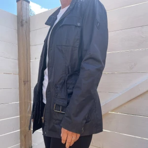 Marinblå höstjacka - Marinblå vaxad jacka med skärp. Sparsamt använd.