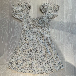 Blommig klänning från H&M - Säljer en superfin blommig klänning från H&M i linneblandning. Den har korta puffärmar och ett sött blommönster i fina färger färger. Perfekt skick och har resor i bak så passar M-L!🥰