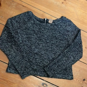 Grå stickad tröja - En grå stickad tröja med dragkedja bak. 