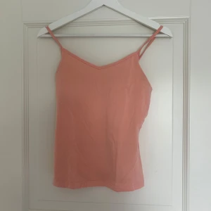 Persikofärgad linnetopp - Säljer en söt persikofärgad linnetopp med smala axelband. Skulle säga att den kan passa S också.