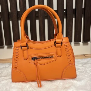 Handväska - Säljer den här superfina orangea väskan från gina då jag tyvärr har för många väskor så den här får inte tillräckligt med kärlek.  Använd 2 gånger och är i nyskick.  Tillkommer ett långt band också. 