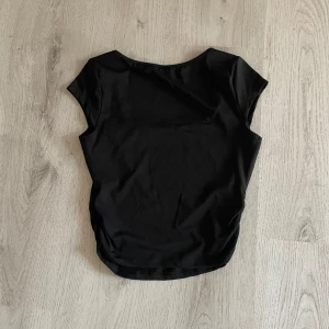 Svart kortärmad topp - Säljer en stilren svart topp med korta ärmar. Perfekt för både vardag och fest. Toppen är i ett mjukt och bekvämt material som känns skönt mot huden.