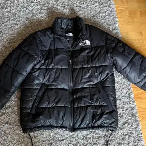 Säljer en svart dunjacka från The North Face. Den är supervarm och perfekt för kalla vinterdagar. Jackan har en dragkedja framtill och är långärmad. Den är i bra skick och redo för nya äventyr!