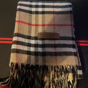 Burberry halsduk - Säljer en rutig halsduk från Burberry. Halsduken är perfekt för att hålla sig varm och stilren under de kallare månaderna.