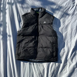 Svart dunväst från Adidas - Snygg Adidas väst i storlek L, perfekt till hösten!