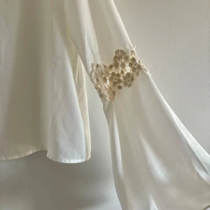 Blus med spets - Utsvängande armar med spets i armvecken.