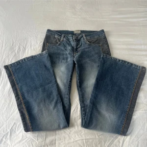 Mörkblå bootcut jeans - Snygga mörkblå bootcut jeans med en klassisk femficksdesign och kontrasterande sömmar. Jeansen har en lätt tvättad look som ger en cool vintagekänsla. Perfekta för en avslappnad stil. Har även cool svart design på sidan som gör den lite extra ”spicell”  innerbenslängd: 79 cm midjemåtten rakt över: 33cm