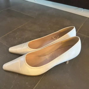 Beige pumps med spetsig tå - Eleganta beige pumps med spetsig tå och låg klack. Perfekta för en stilren look. Tillverkade i ett slätt material som ger en klassisk känsla.