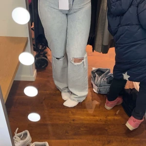 Ljusa jeans med slitningar - Snygga ljusa jeans med slitningar på knäna. De har en bootcut-stil och är högmidjade, vilket ger en trendig look. Perfekta för en avslappnad stil.