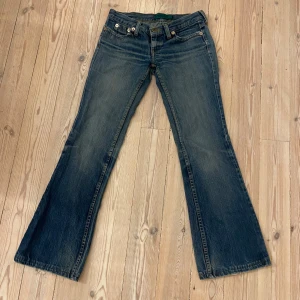 Lågmidjade jeans - Snygga blå lågmidjade bootcut jeans från MNG med en bootcut-stil. De har en klassisk femficksdesign och är lågmidjade. Perfekta för en avslappnad look har lite nötningar vid fötterna men inget man tänker på! Midjemåttet:36-37 cm rakt över Innerbenslängd: 73cm ungefär 