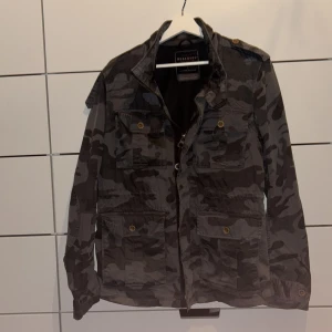 Camouflagejacka från Reserved - Säljer en cool camouflagejacka från Reserved i storlek L men passar M Jackan har flera fickor med knappar och dragkedja framtill. Perfekt för en avslappnad stil.