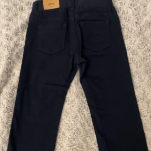Mörkblå byxor från Lindex - Säljer ett par mörkblå byxor från Lindex med rak passform och normal midja. Byxorna har en enkel design med två bakfickor och är perfekta för vardagsbruk. De är tillverkade för barn i åldern 1½-2 år. (Säljer hälften av ordinarie priset på grund av att de aldrig är använda + med prislapp)