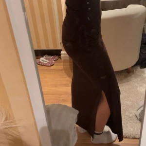 Brun långklänning från Kappahl - Snygg brun långklänning från Kappahl aldrig använt med en elegant slits på sidan + prislappen kvar. Klänningen är ärmlös och har en tight passform som framhäver figuren. Perfekt för en stilren look.