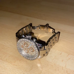 Silverfärgad klocka med strass - Snygg silverfärgad klocka ifrån Marc Ecko med strass runt urtavlan. Klockan har en robust länkarmband och flera små urtavlor inuti. Perfekt för den som gillar en glittrig och iögonfallande stil. Passar bra till både vardag och speciella tillfällen.
