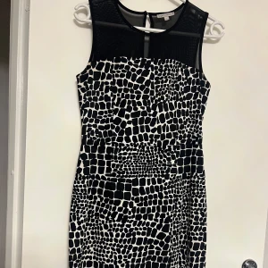 Svartvit mönstrad klänning - Snygg svartvit klänning med ett unikt mönster och transparenta detaljer upptill. Perfekt för en stilren look. Klänningen är ärmlös och har en smickrande passform.