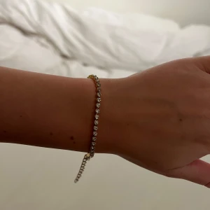 Tennis armband  - Elegant guldarmband med små glittriga stenar som ger en lyxig känsla. Armbandet har en justerbar kedja och en säker låsning. Perfekt för att lägga till lite extra glamour till din outfit.