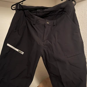 Svarta shorts från Peak Performance - Snygga svart/gråa lite längre shorts från Peak Performance som aldrig är använda, dragkedja och knapp framtill. Byxorna har en ficka med dragkedja på sidan och är till för att ha utomhus. Storlek M och äkta såklart! Nypris 1500kr💕
