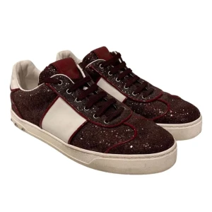 Valentino flycrews - Snygga sneakers i vinrött med glittrig yta och vita detaljer. Skorna har en unik design med nitar på hälen och snörning framtill. Perfekta för att ge din outfit en extra touch. MVH scandicfashion 