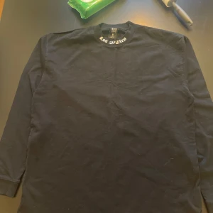 Svart långärmad tröja med Los Angeles-tryck från black squads  - Säljer en svart långärmad tröja från black squad med stort Los Angeles-tryck på ryggen och texten 'Fear is temporary - Regret is forever' längst ner. Perfekt för en avslappnad stil.