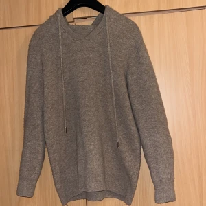 Grå hoodie i kashmir - Säljer en stilren och mjuk grå hoodie i kashmir. Tröjan har långa ärmar och en klassisk huva med dragsko. Perfekt för kyliga dagar och ger en lyxig känsla. Passar både till vardags och mysiga hemmakvällar.Pris kan diskuteras på snabbköp!!!
