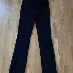 Svarta bootcut jeans - Snygga svarta bootcut byxor från Cubus med en klassisk design och knappdetalj i midjan. Perfekta för en stilren look. Byxorna är tillverkade i ett bekvämt material. Helt nya bara provade en gång. Midjemått är ca 34cm och innerbenslängd 76 cm. Säljer då de är lite för små för mig. Skriv för fler bilder eller frågor! 