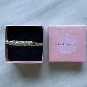 Armband Glittrigt  - Elegant armband med en flätad rem och en glittrig detalj i silver. Perfekt för att ge en touch av glamour till din outfit💕