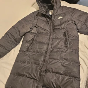 Svart lång Nikejacka  - Säljer en Nike Windrunner PrimaLoft. En lång  jacka har använt den typ 4/5 gånger och vill sälja den eftersom den inte passar mig och den är i perfekt skick som en helt ny jacka köpte den för 3.499 från Nike. 